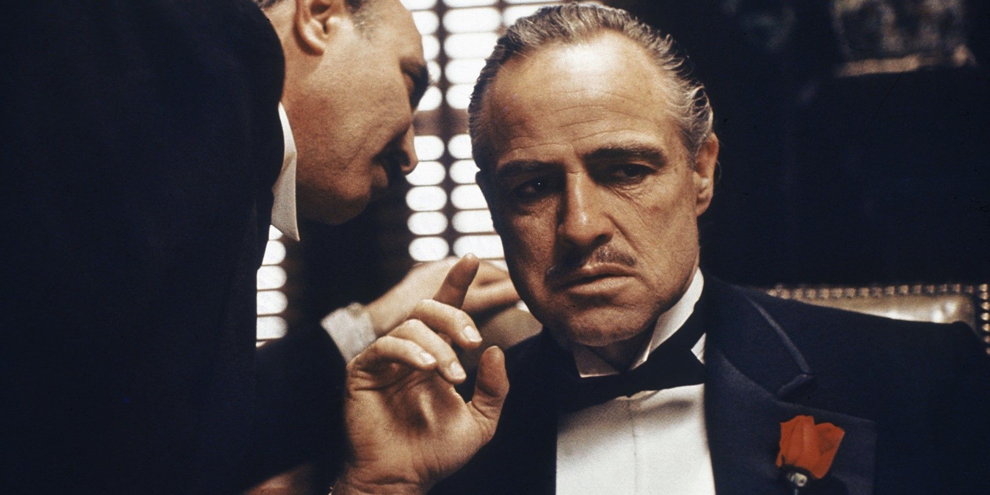A man whispers in the ear of Don Vito Corleone in The Godfather.