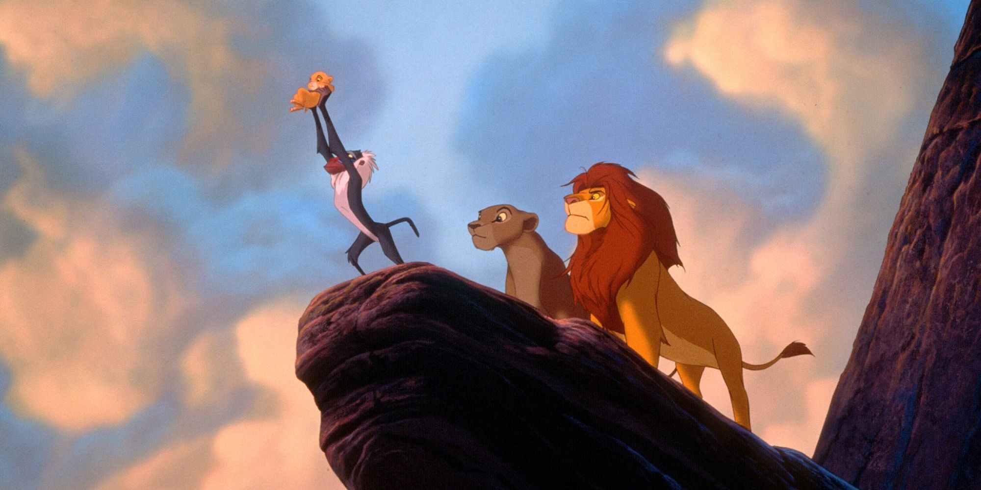 Rafiki holding Simba at Pride Rock in The Lion King.