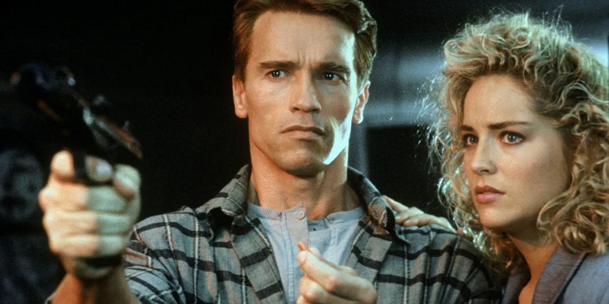 Quaid is pointing a gun at someone, and Laurie is standing next to him. 