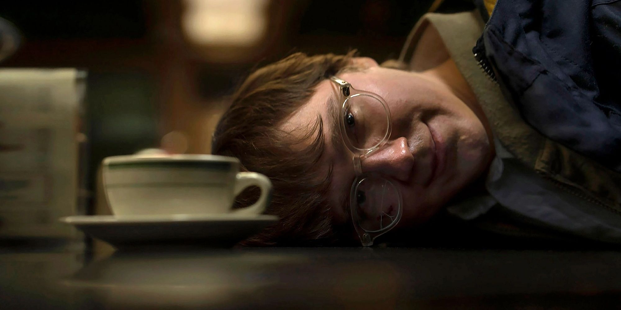 The Riddler with his head down on the coffee shop counter in Batman.
