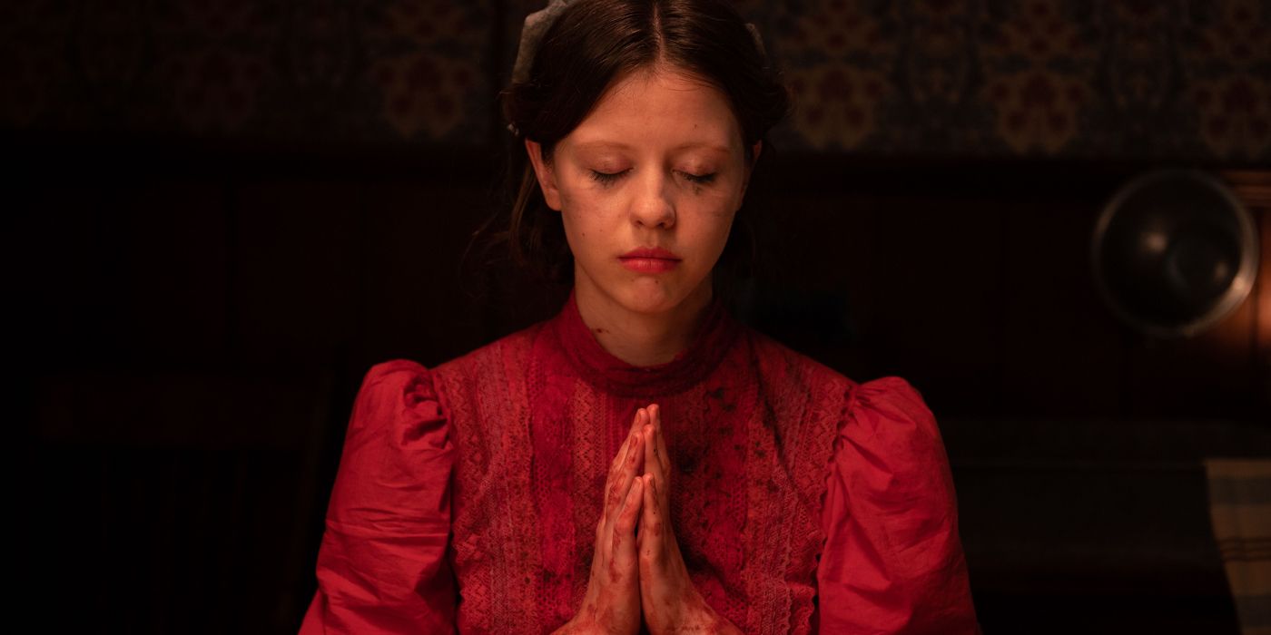 Pearl, played by Mia Goth, prays with her eyes closed in The Pearl.