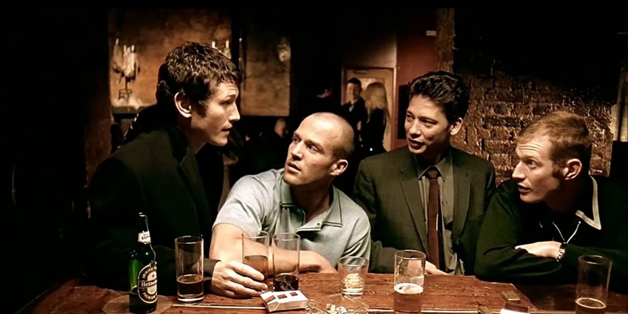 Four men are sitting in a bar and talking to each other