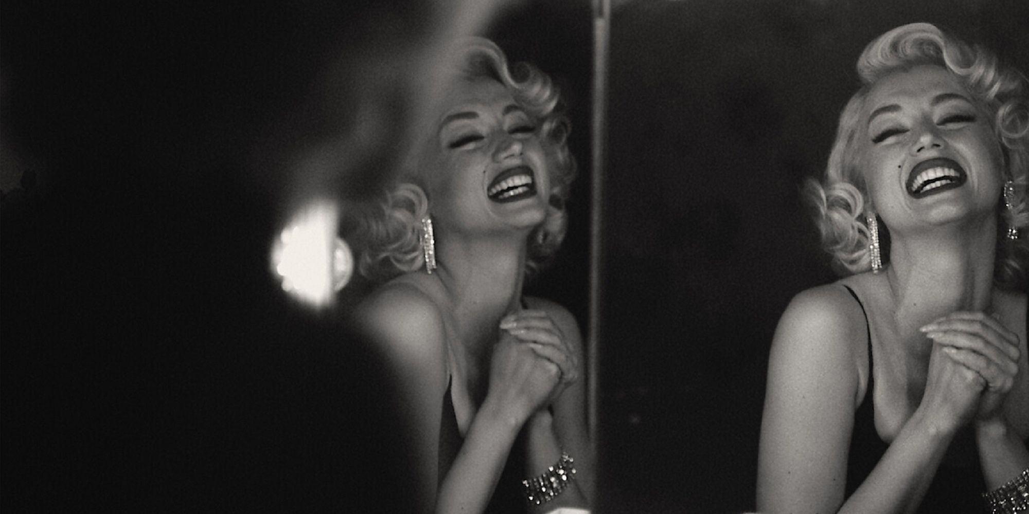 Ana de Armas as Marilyn Monroe smiling in front of a mirror in Blonde.