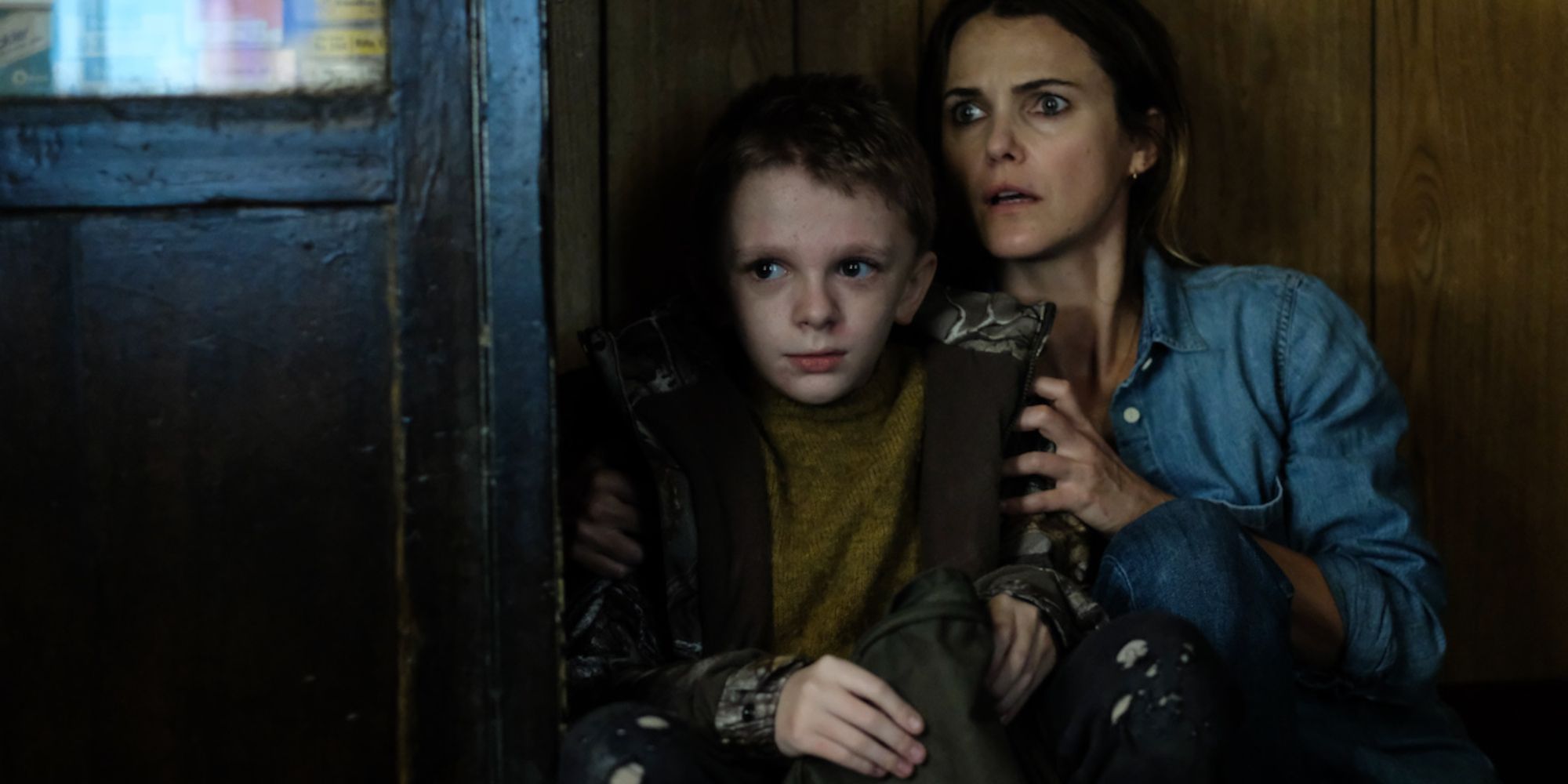 Keri Russell and Jeremy T. Thomas hide in the corner of the house. 