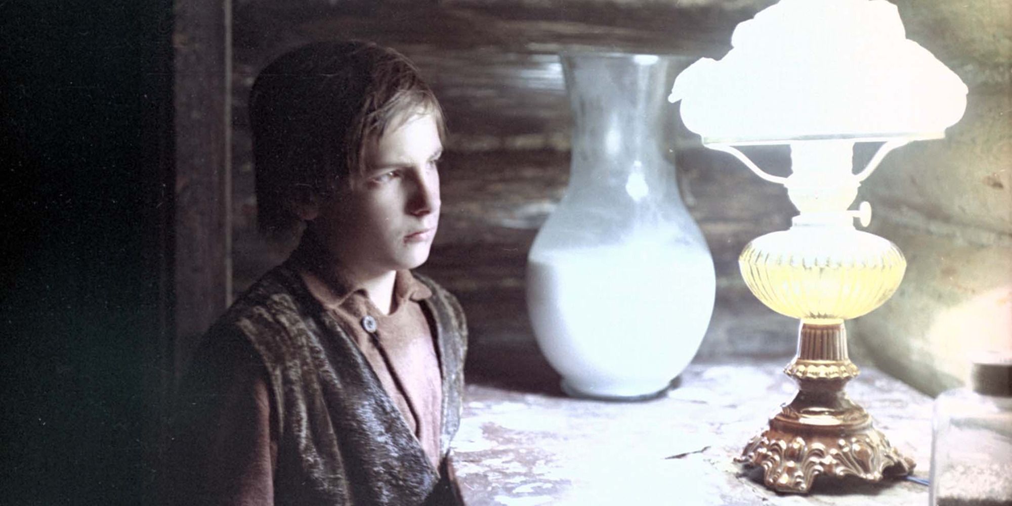 The child from The Mirror looks at the lamp on the table.