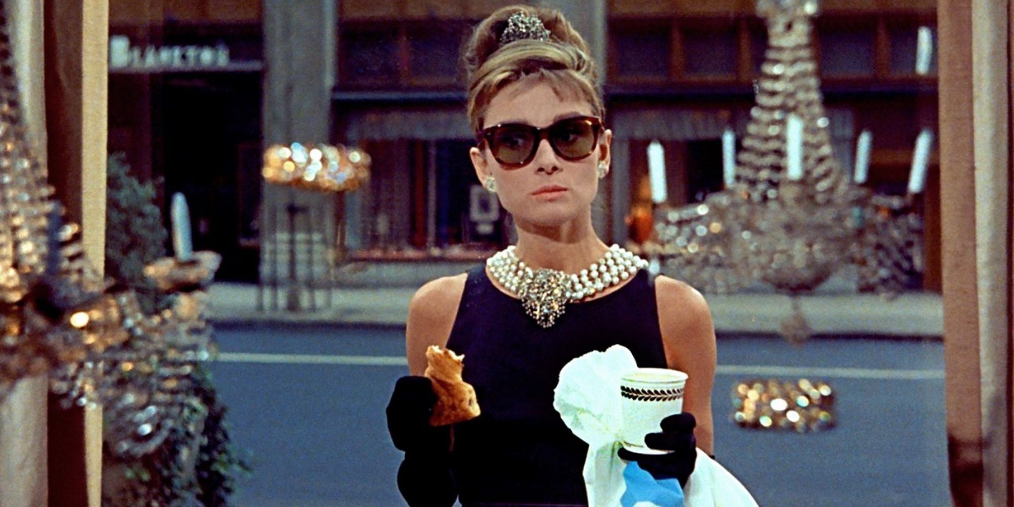 Holly Golightly holding a bag and a cup of coffee in Breakfast at Tiffany's.