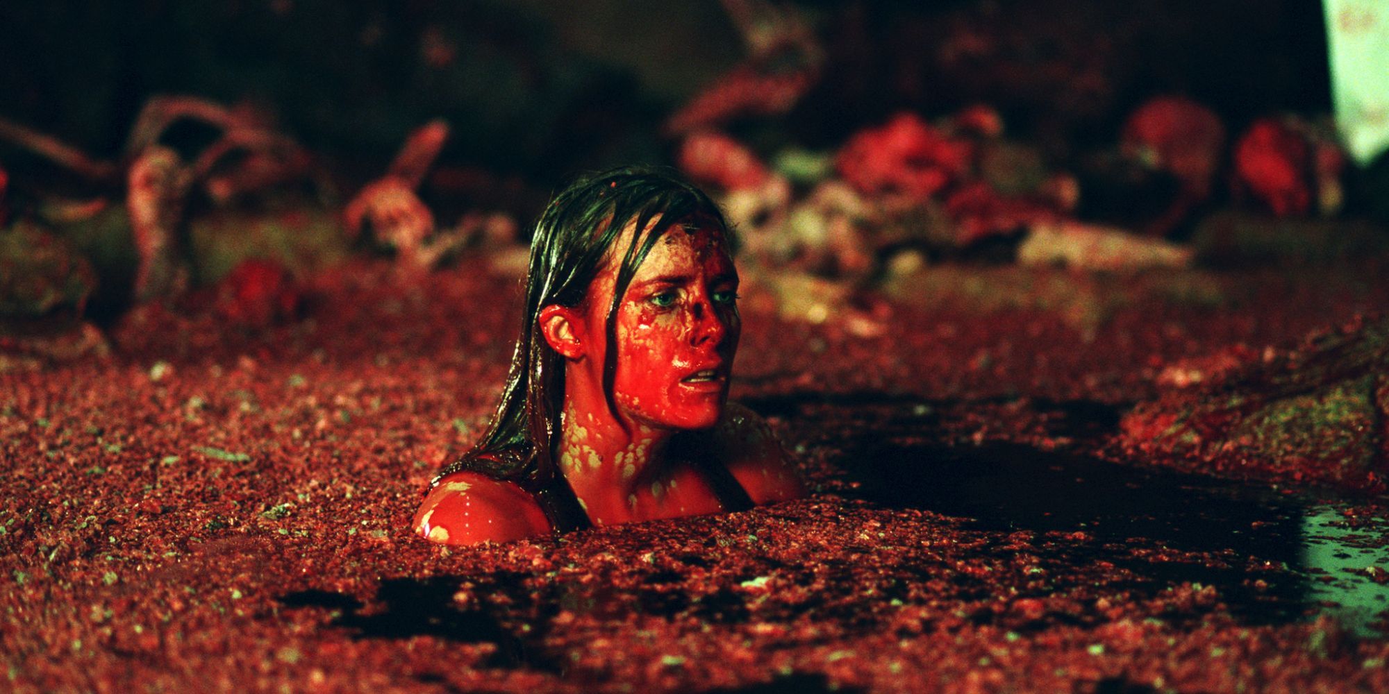 A woman soaked in blood swims in a pool of human carcasses in The Descent (2005)