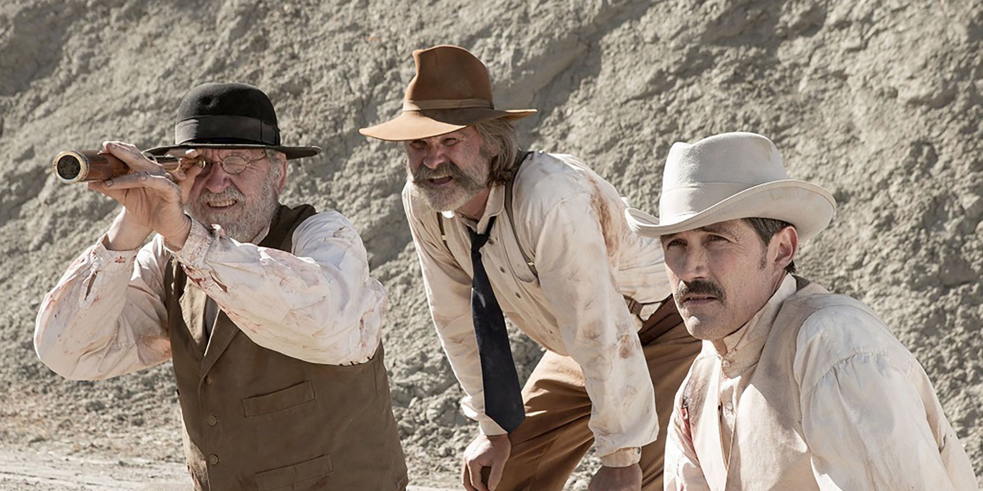 Richard Jenkins, Kurt Russell, and Matthew Fox stare into the distance as they sit in a valley in Bone Tomahawk.