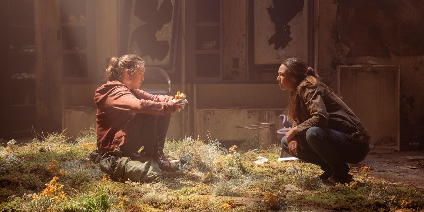 Tess is eating a sandwich while talking to Tess in an abandoned building in a scene from The Last of Us.