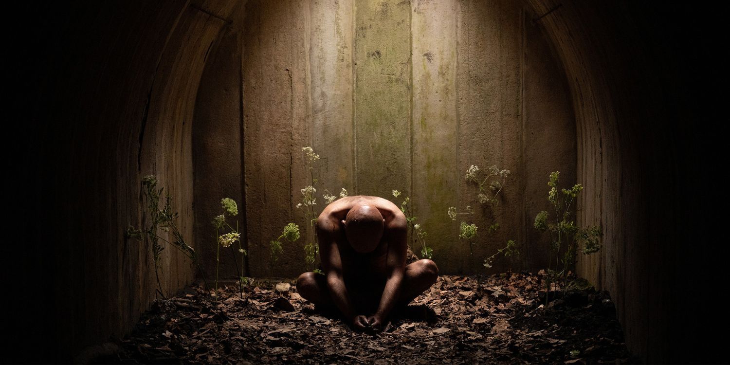 Geoffrey sits in a room naked looking down
