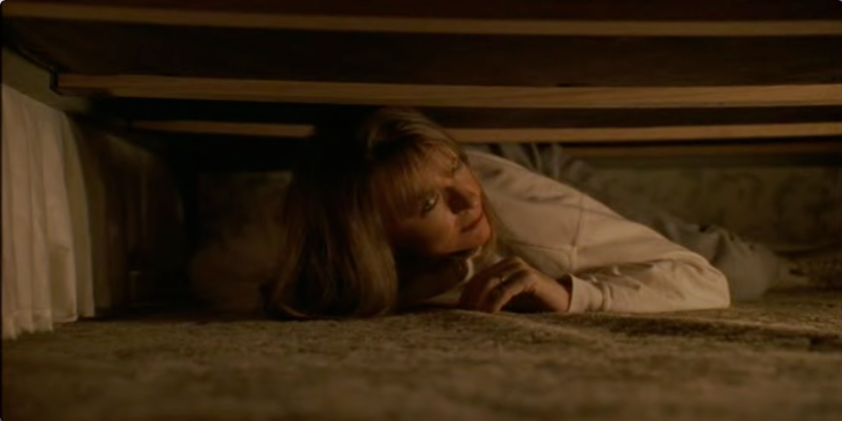 Diane Keaton as Carol Lipton hides under a bed in Manhattan Murder Mystery.